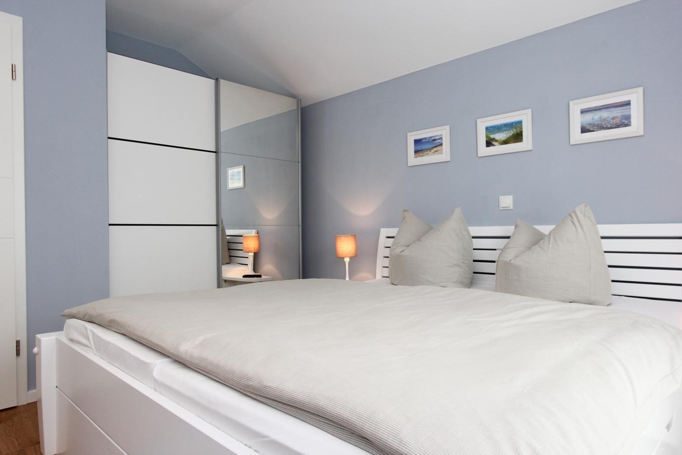 Schlafzimmer mit Bett, Kleiderschrank und Wandbildern