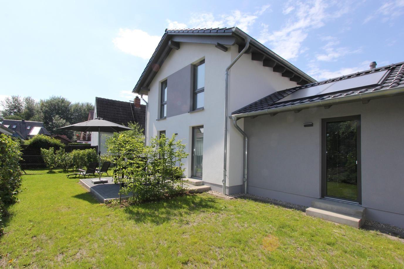 Moderne Villa mit Garten, Sonnenschutz und Terrasse. Haus mit Fenstern und Dach.