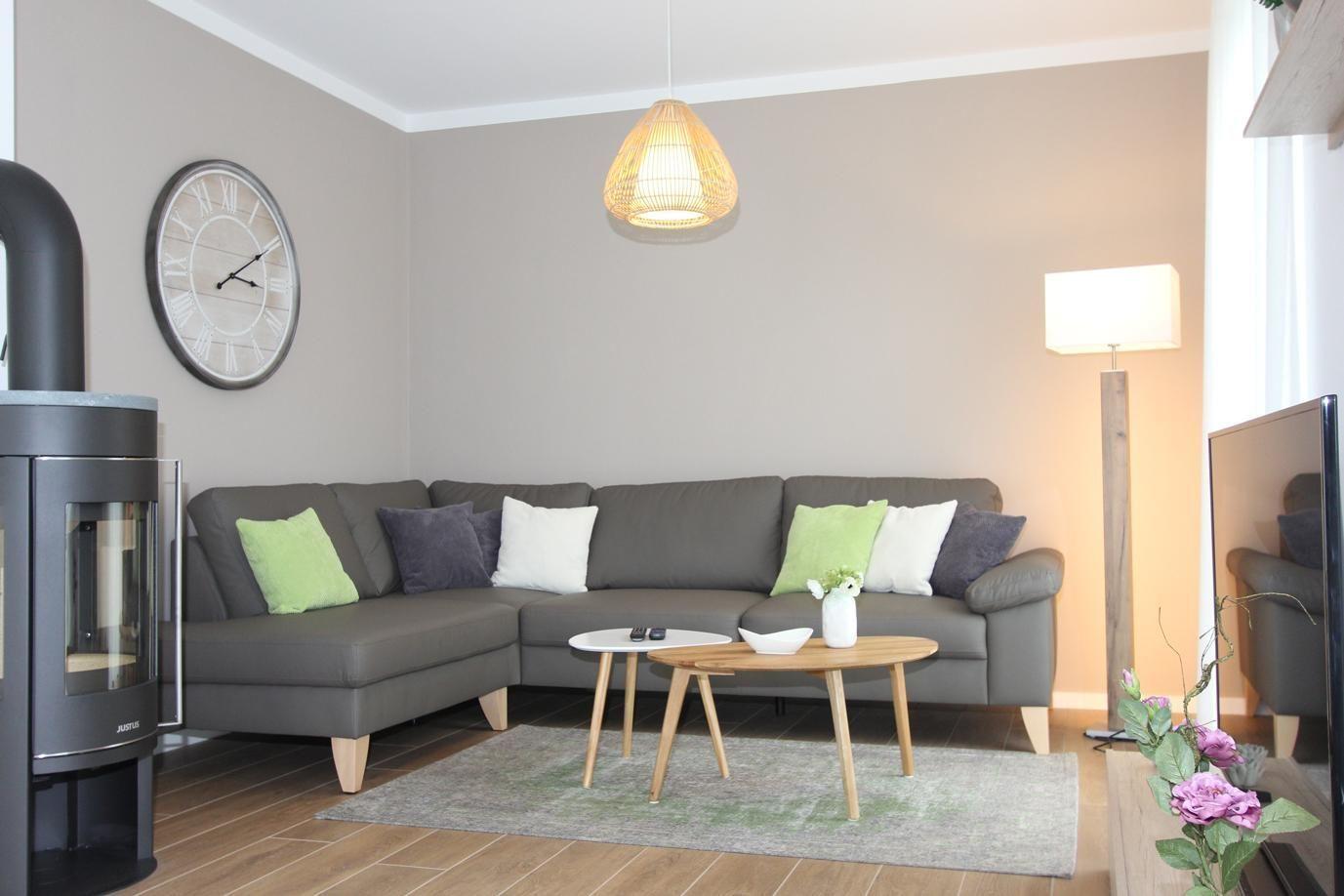 Wohnzimmer mit grauem Sofa, Holztisch und Wanduhr.
