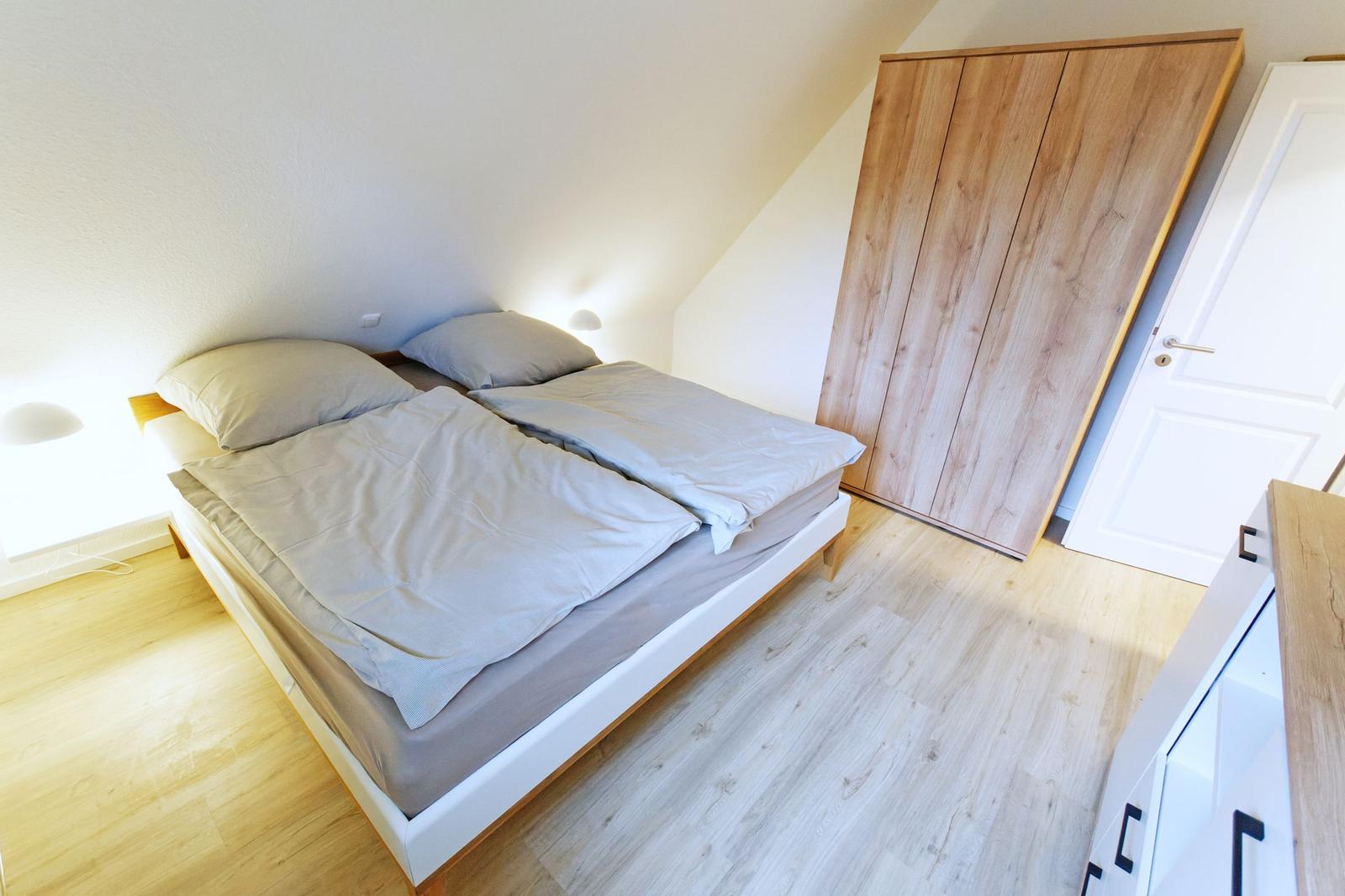 Schlafzimmer mit Doppelbett, Holzboden und Kleiderschrank.