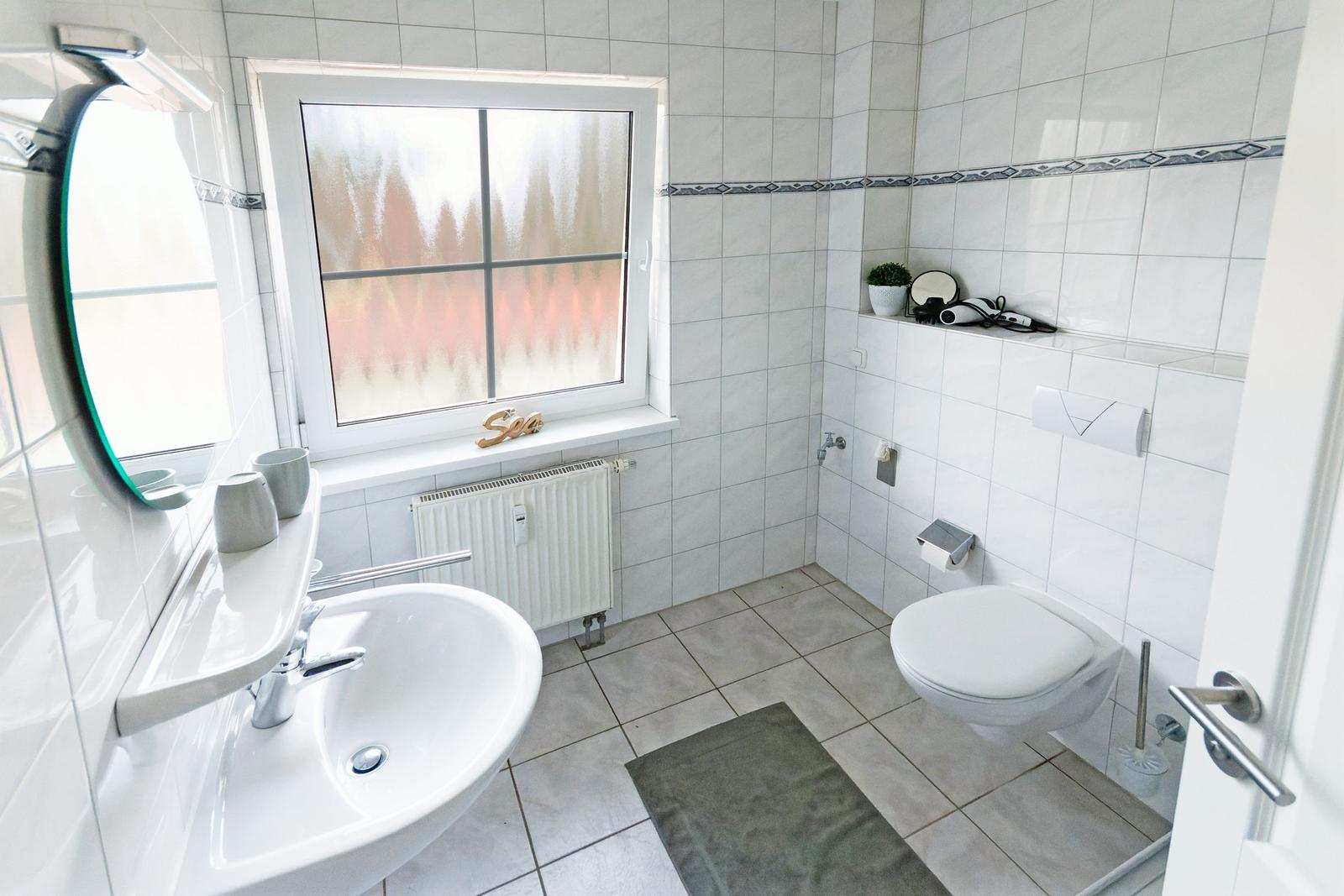 Badezimmer mit Toilette, Waschbecken und Fenster mit getöntem Glas.