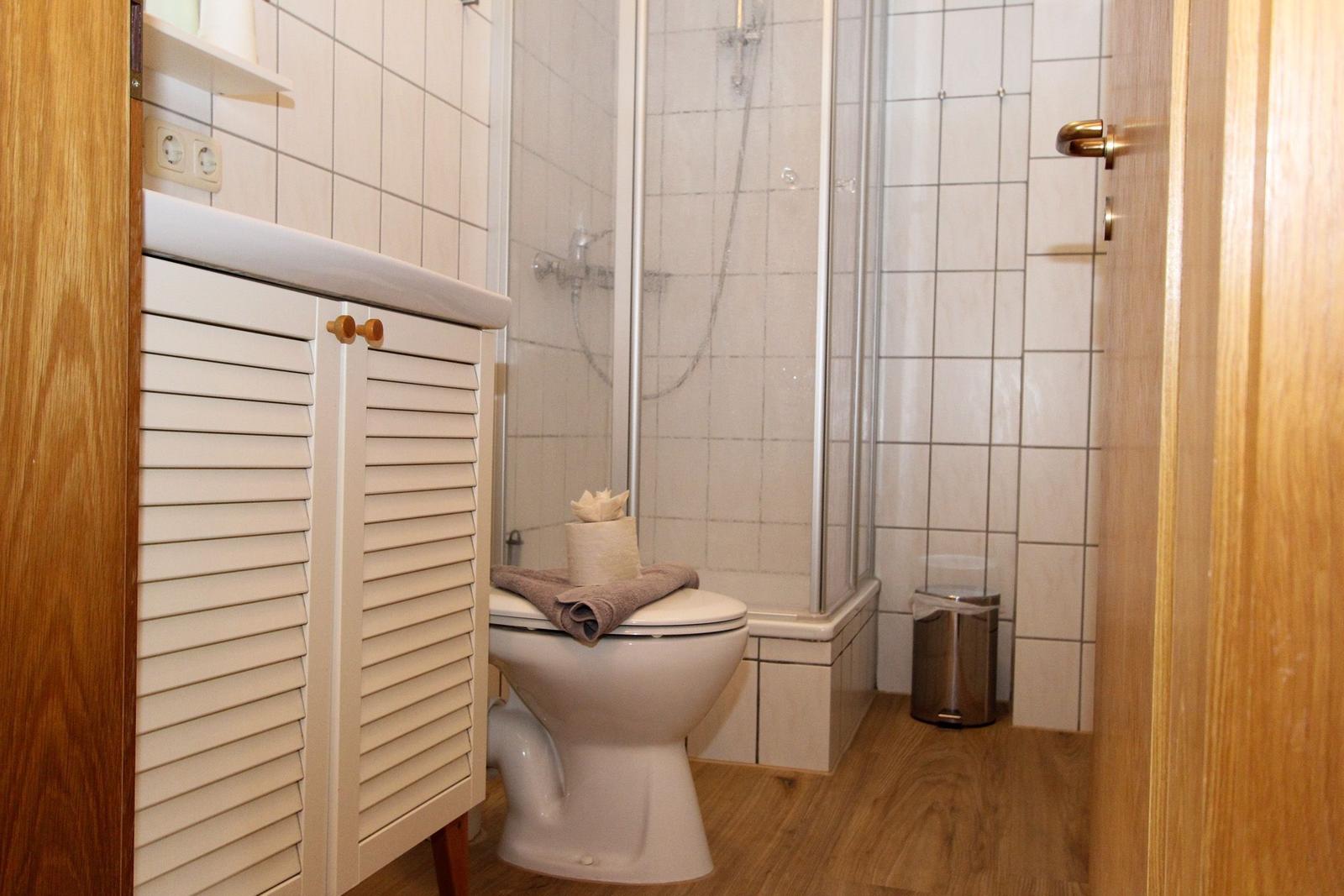 Badezimmer mit Toilette, Dusche und Waschbecken mit Holzfußboden.