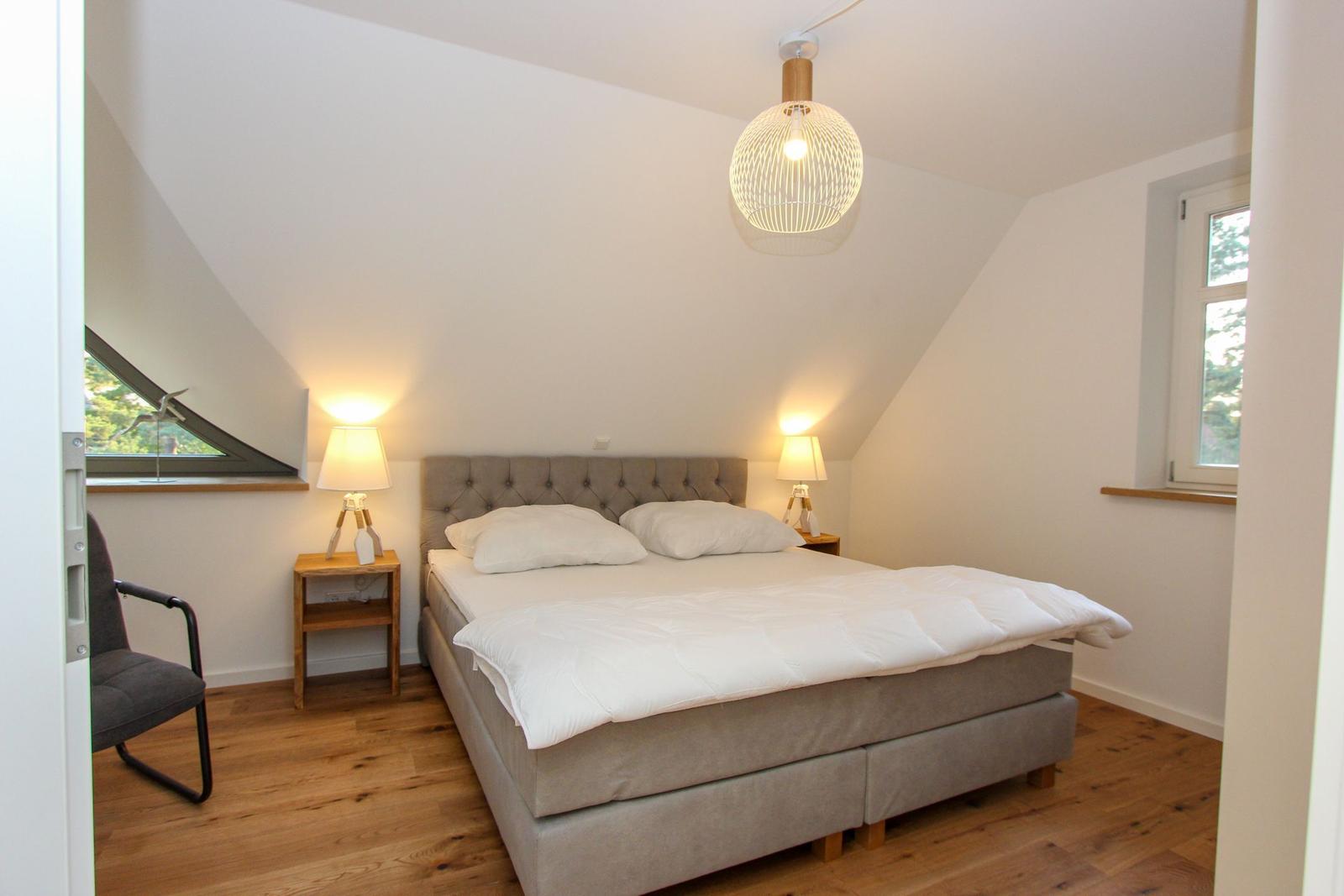 Schlafzimmer mit Doppelbett, zwei Nachttischen und einem Fenster.