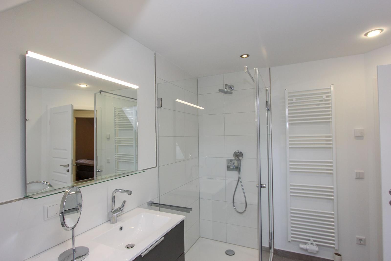 Badezimmer mit Dusche, Waschbecken und Spiegel