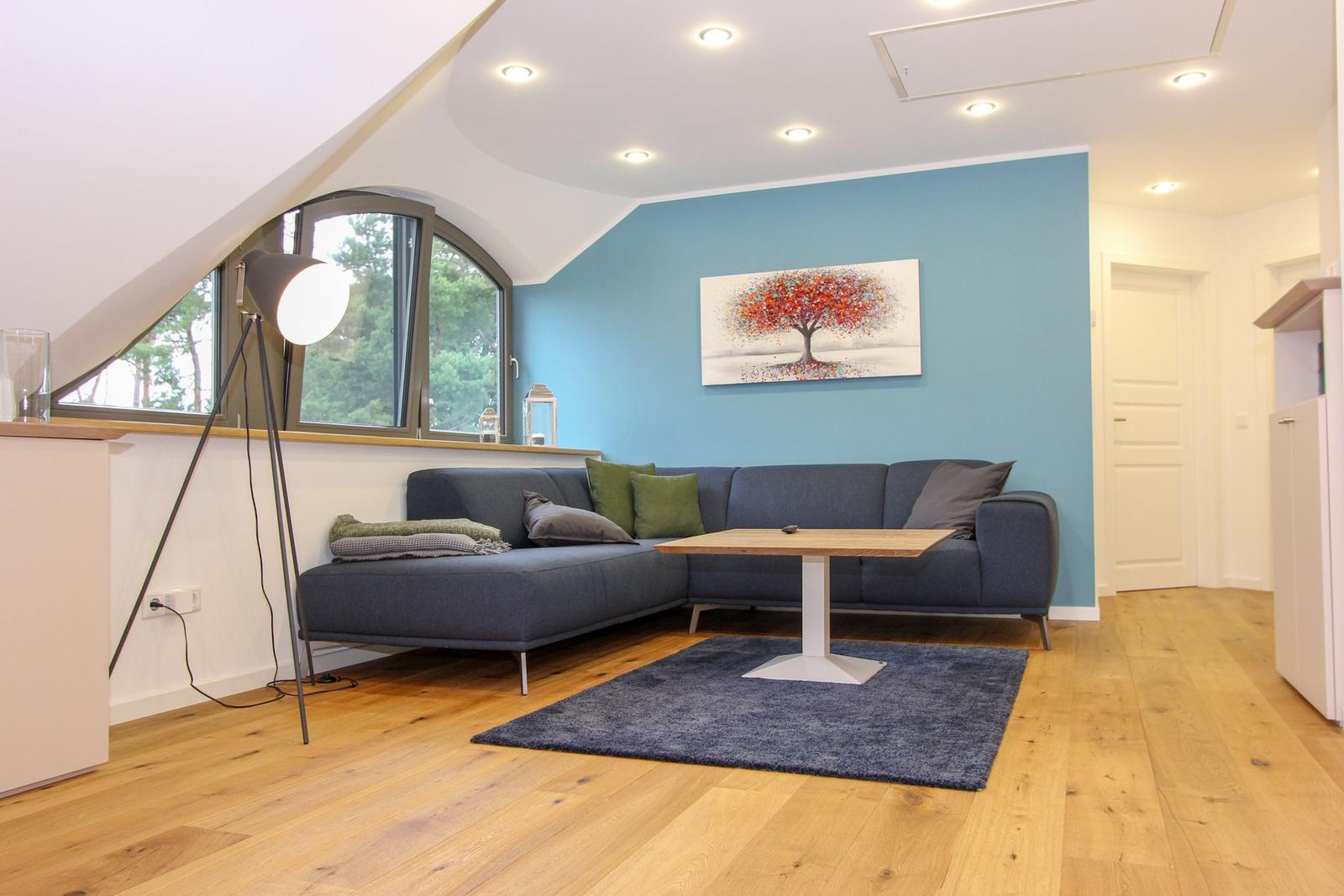 Wohnzimmer mit Sofa, Tisch und Fenster. Wandbild und Holzboden.