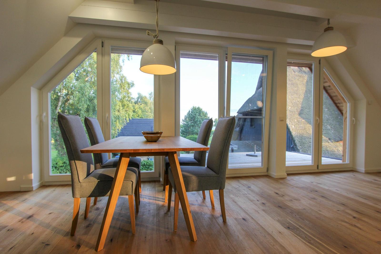 Esszimmer mit Holztisch, Stühlen und großen Fenstern zum Garten