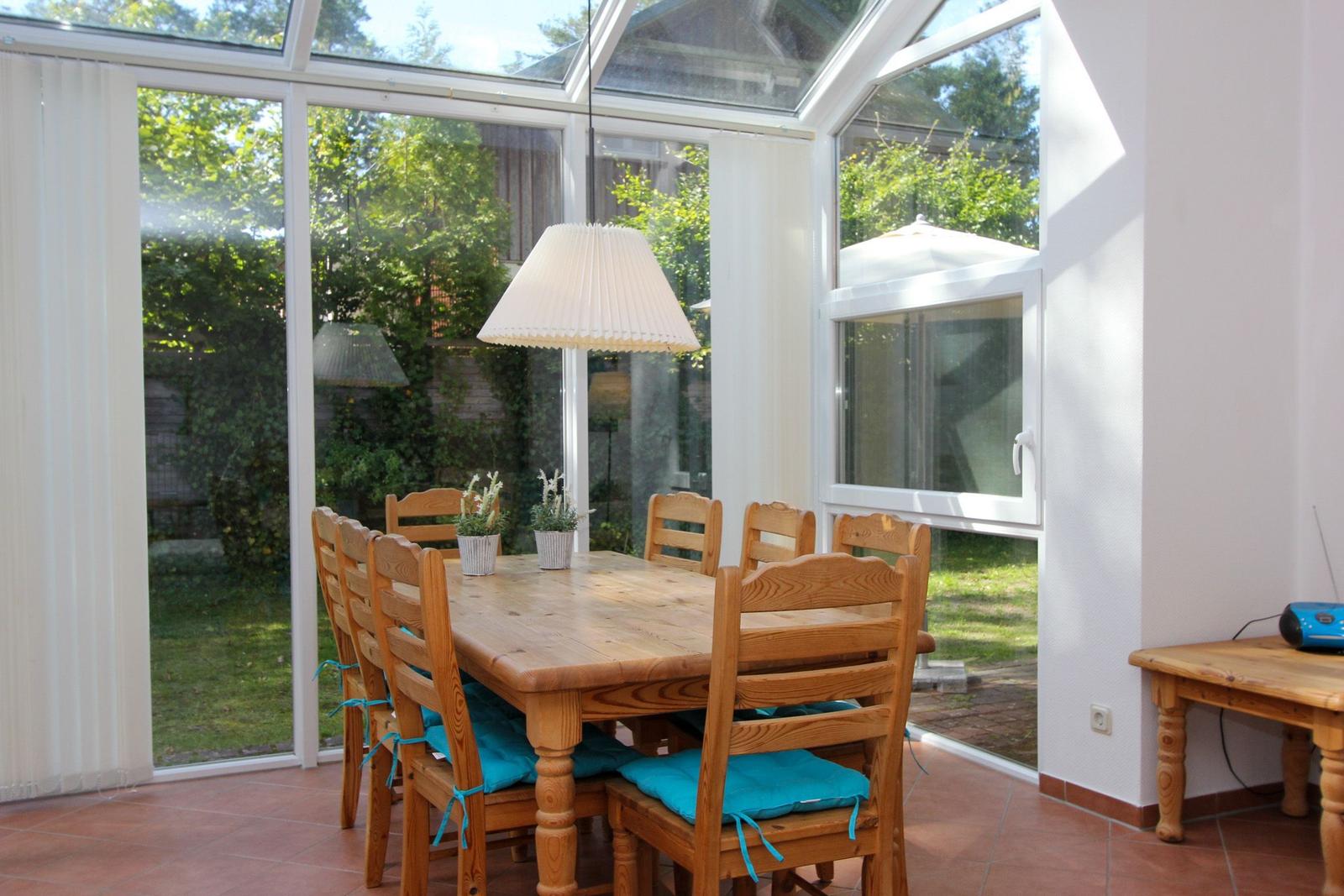 Esszimmer mit Holztisch, Stühlen und Blick auf Garten