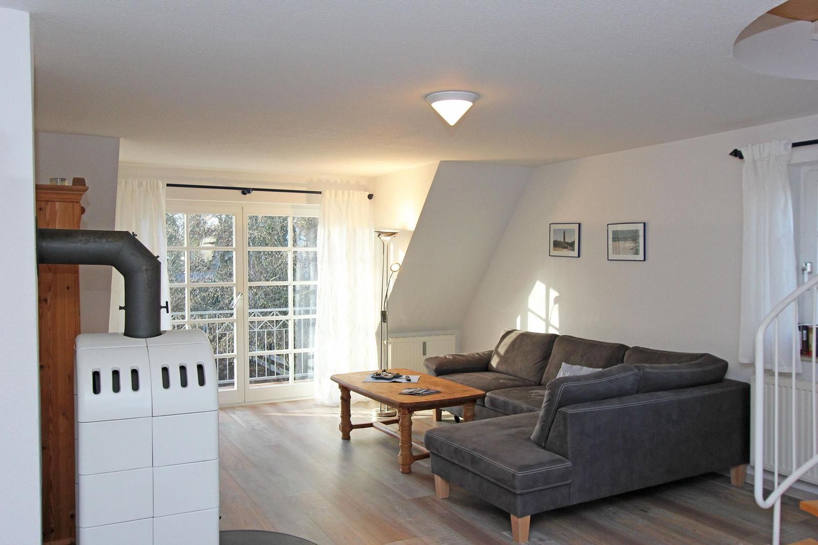 Wohnzimmer mit Sofa, Holztisch und Schiebetür zum Balkon.