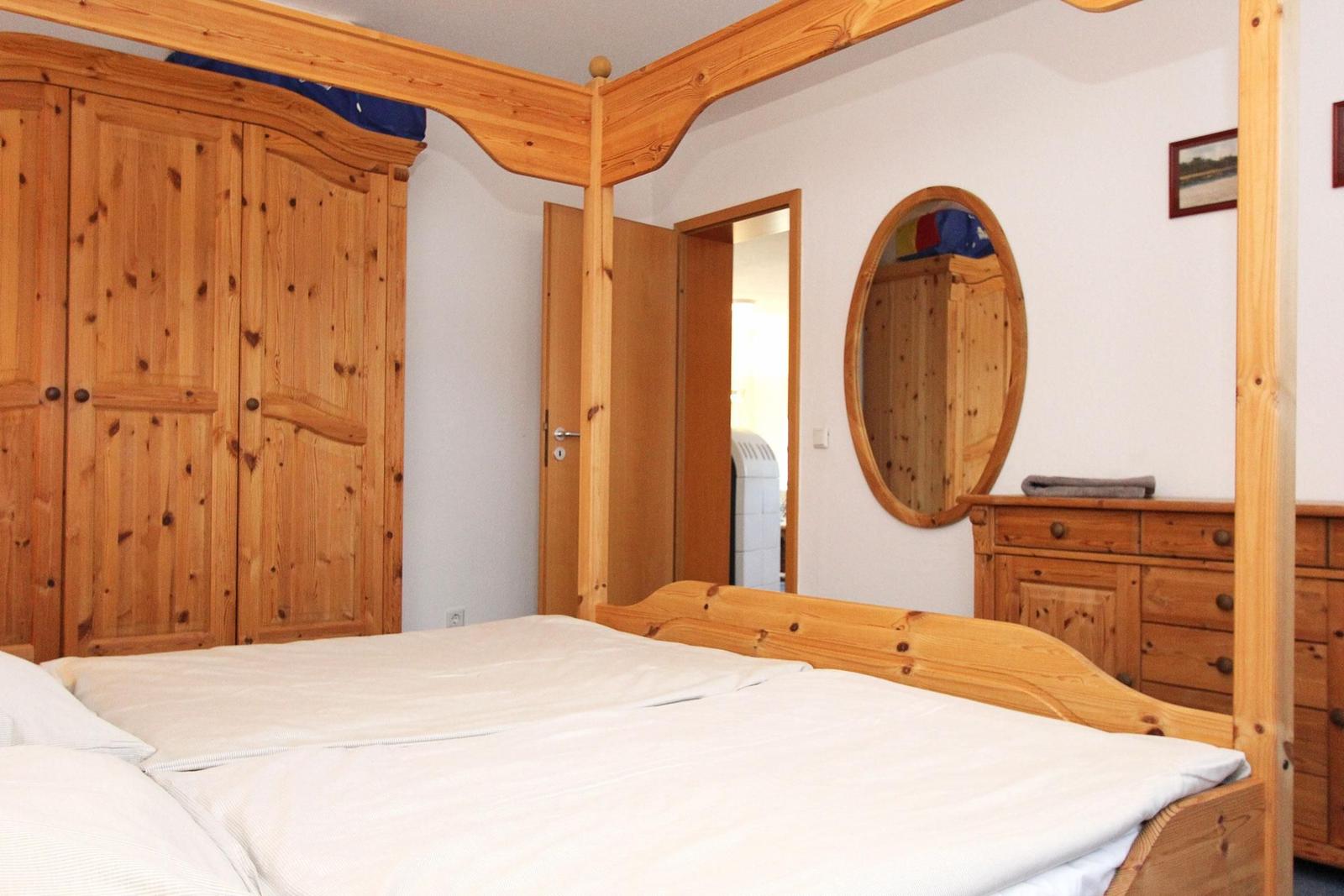 Schlafzimmer mit Holzbett, Kleiderschrank und Schminktisch