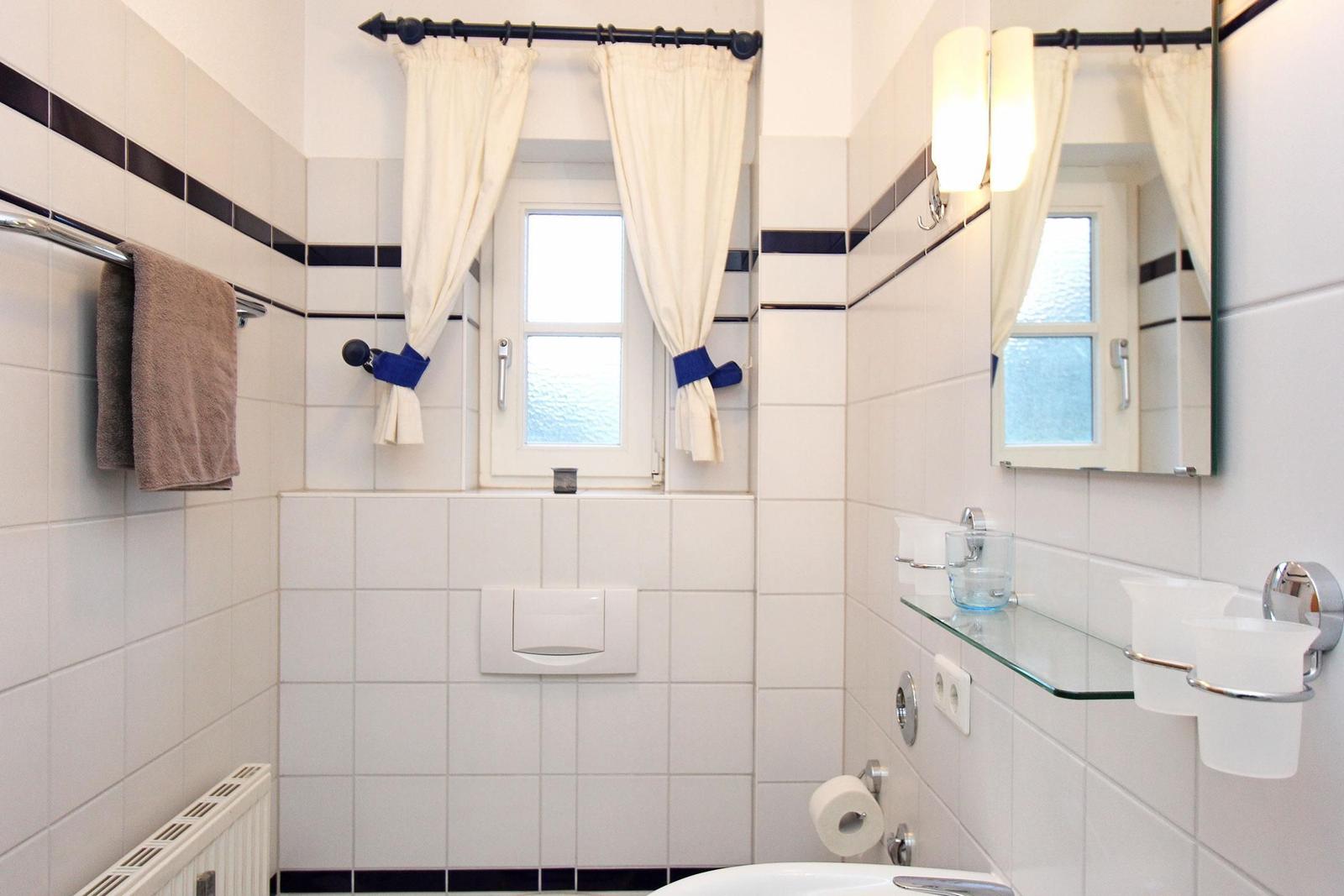 Badezimmer mit Fenster, Spiegel und Toilettenpapierhalter