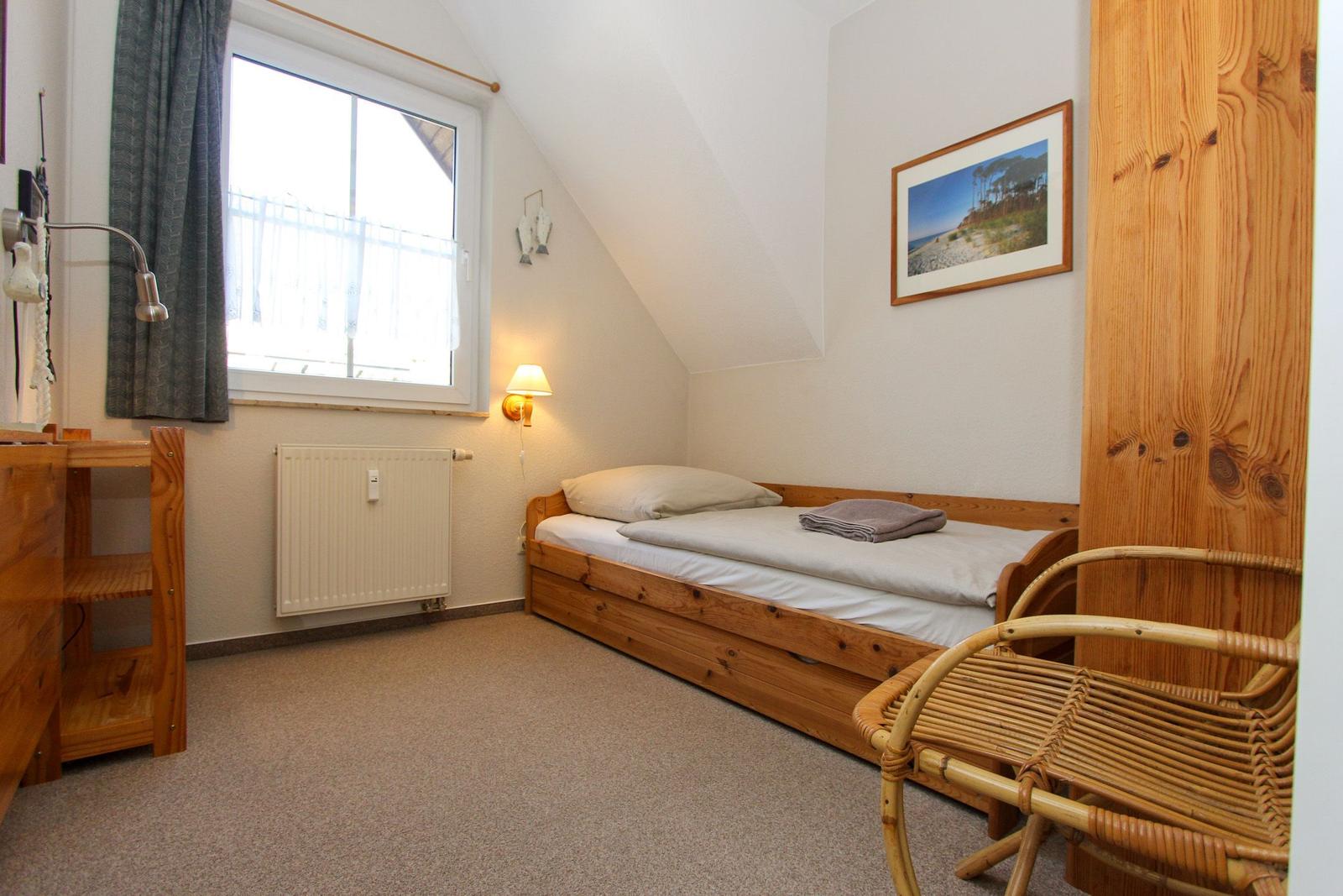 Ein Schlafzimmer mit Holzbett, Fenster und Wandleuchte.