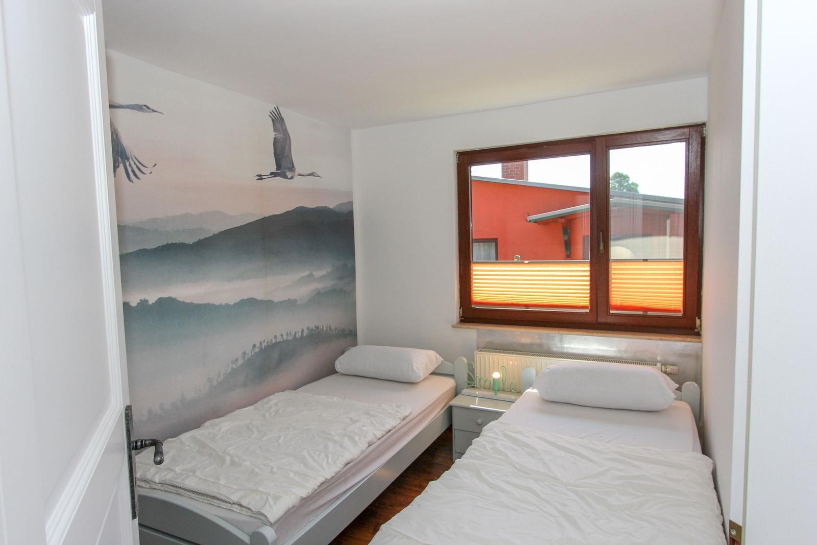 Zwei Einzelbetten mit weißen Bettwäsche. Wandbild mit Schwanen und Bergen. Fenster mit Holzrahmen.