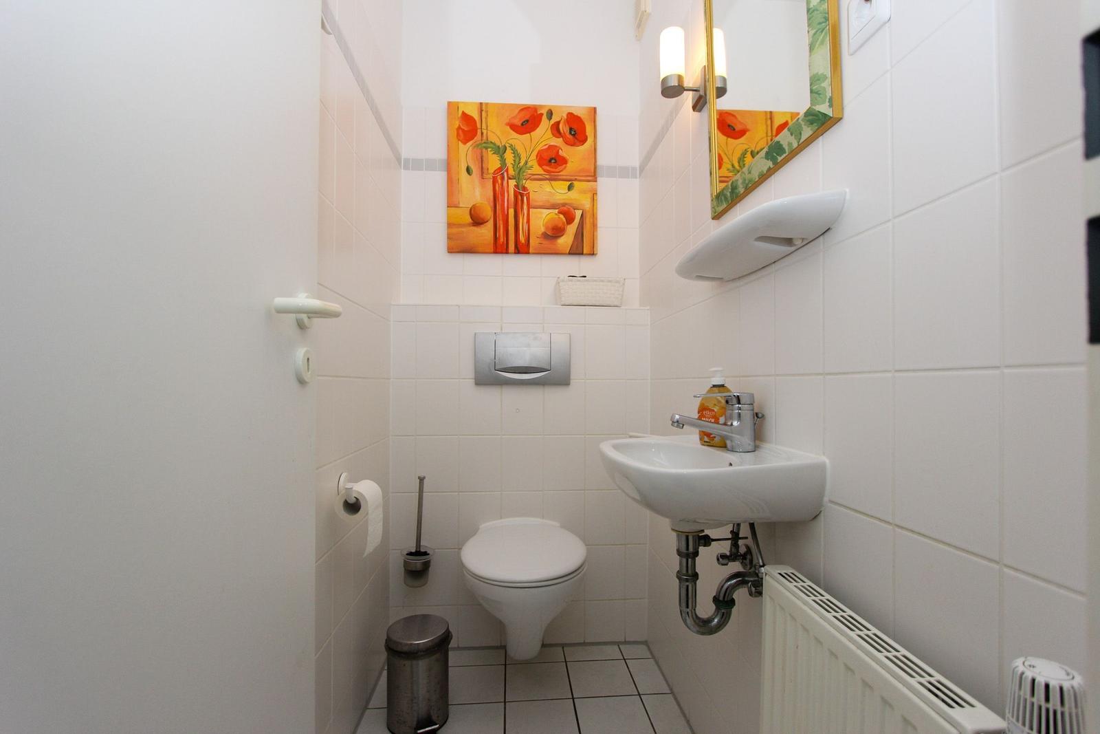 Badezimmer mit Toilette, Waschbecken und Wandbild mit Mohnblumen.