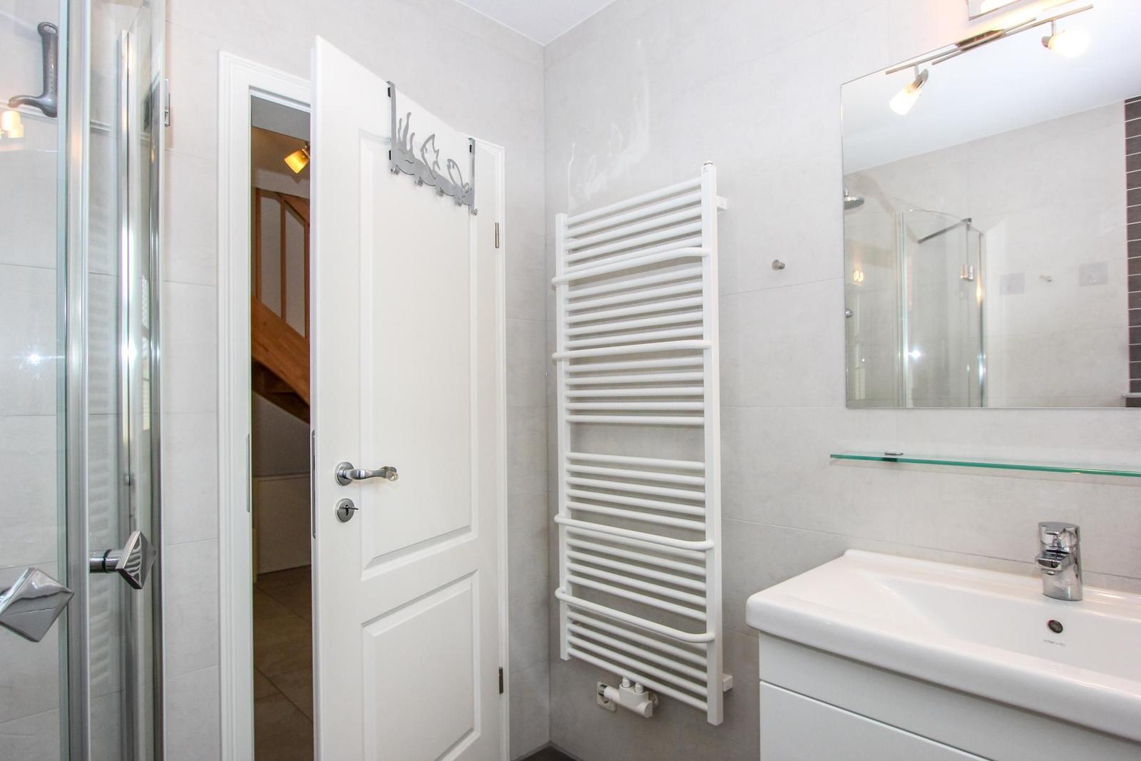 Badezimmer mit Dusche, Waschbecken und Heizkörper.
