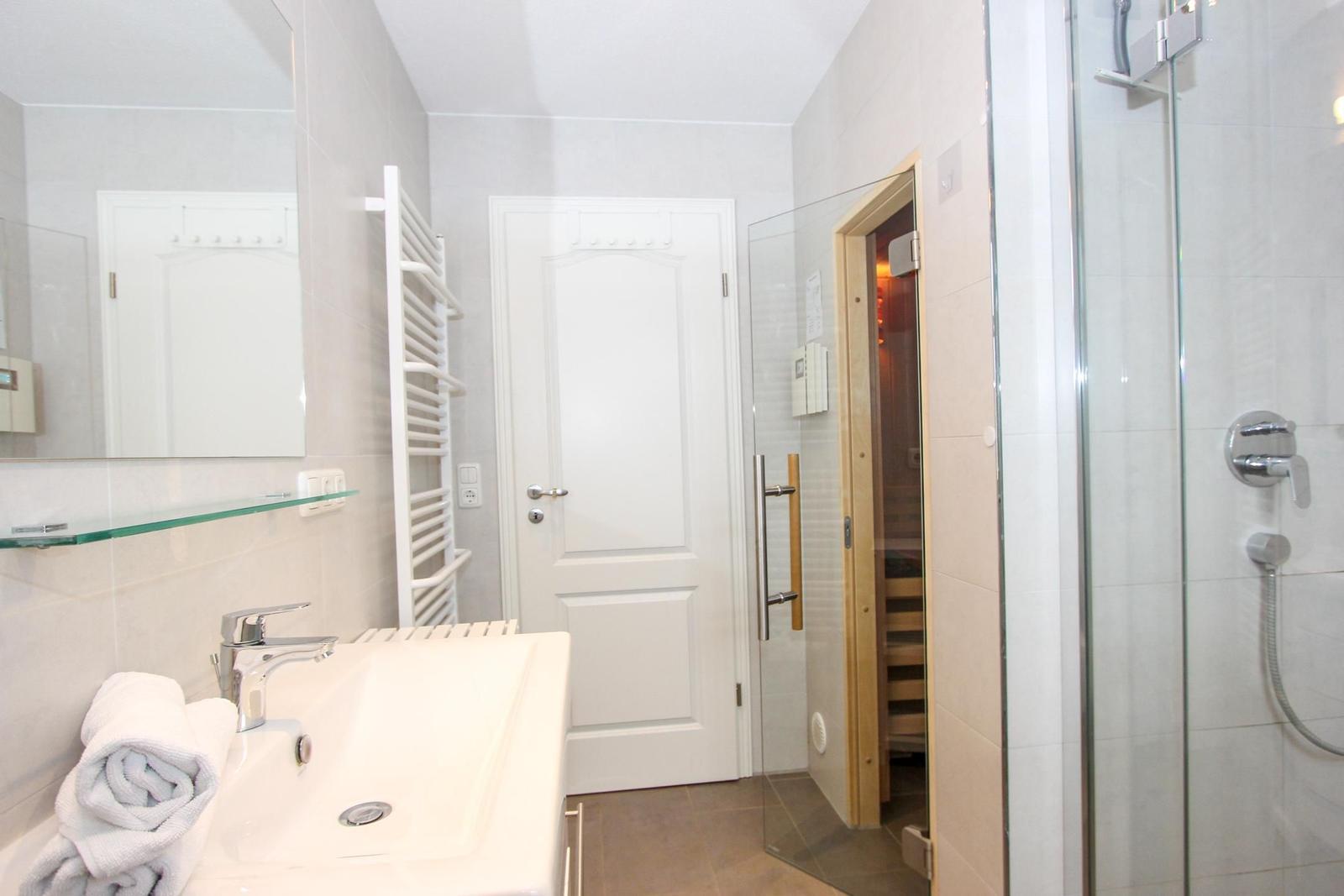 Badezimmer mit Dusche, Waschbecken und Sauna