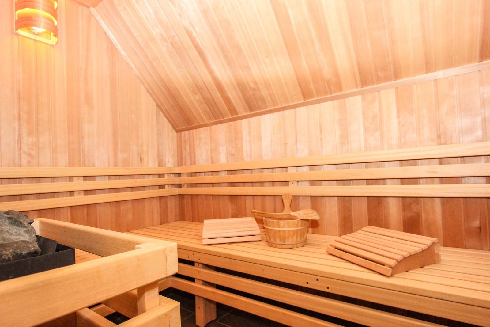 Sauna mit Holzbank, Eimer und Stein im Dachbereich.