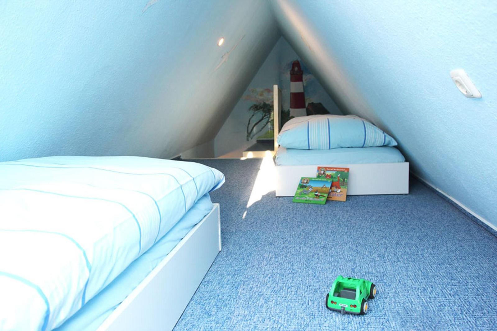 Zimmer mit zwei Betten, blauer Wandfarbe und Spielzeug auf dem Boden.