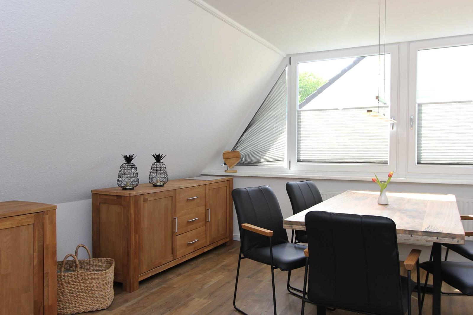 Esszimmer mit Holztisch, schwarzen Stühlen und Schrank an der Wand.