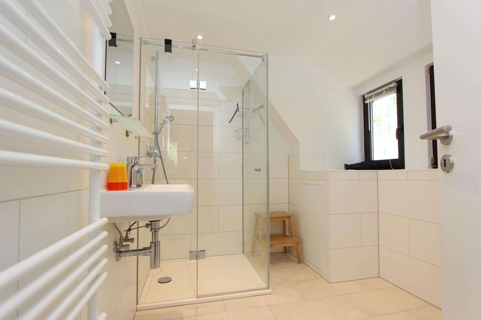 Badezimmer mit Dusche, Waschbecken und Heizkörper