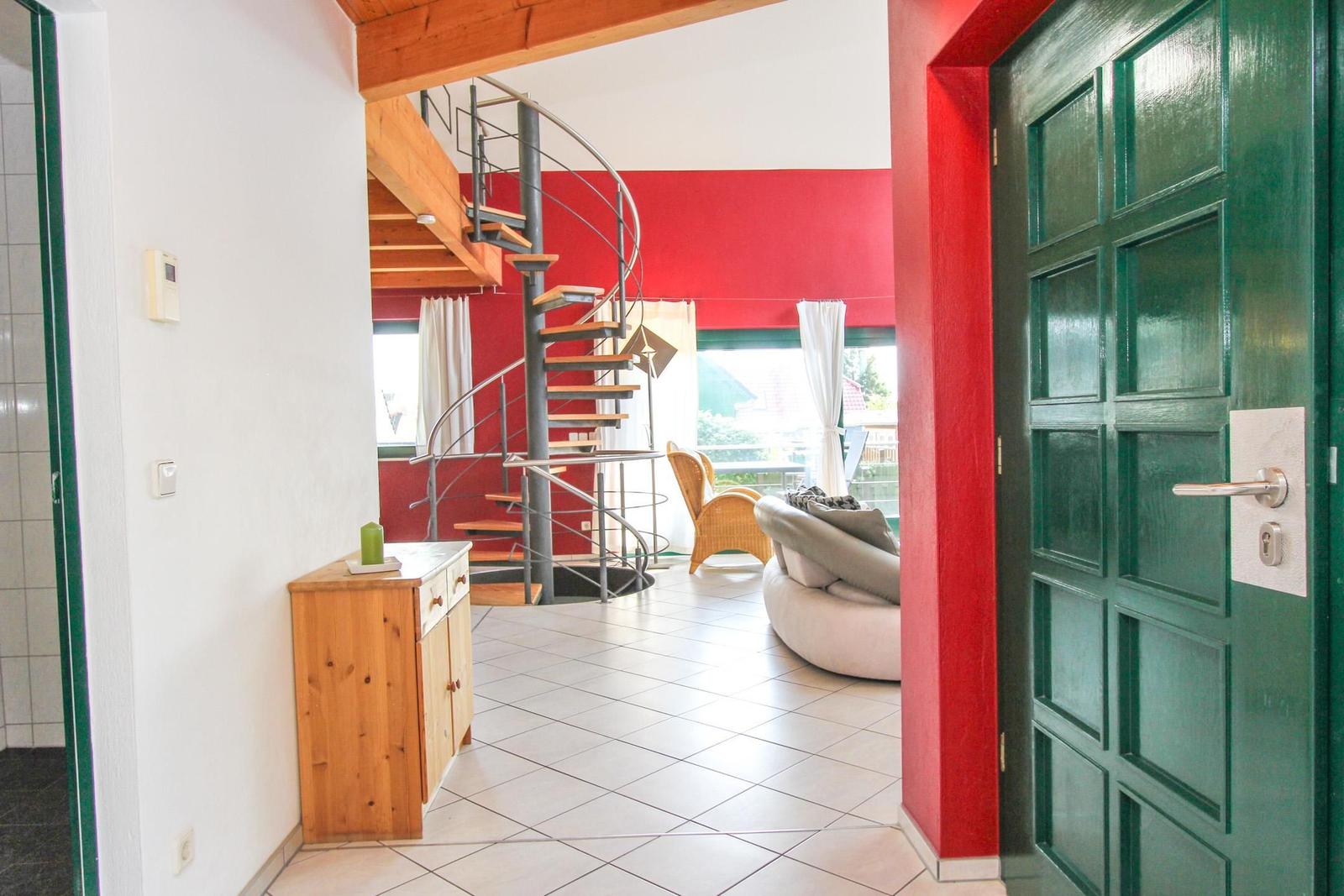 Haus mit Eingangstür, Treppe und Wohnbereich mit Sofa und Stuhl.