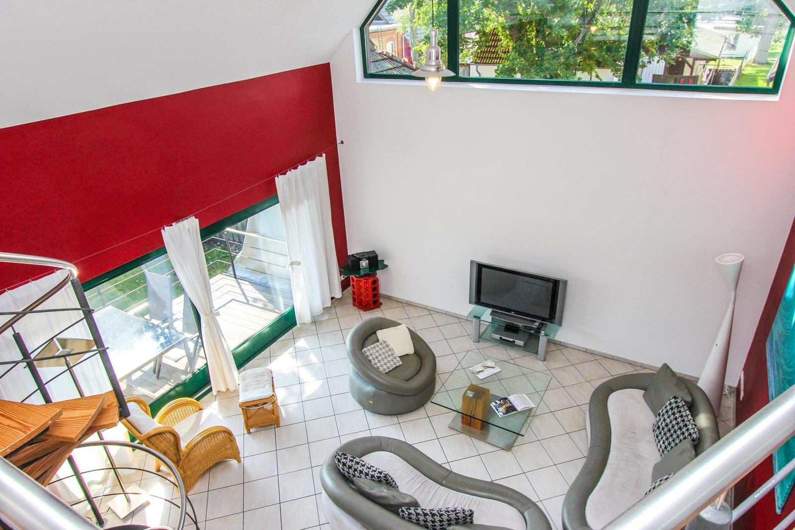 Wohnraum mit Glasboden, Sofa, Fernseher und Blick auf Balkon.