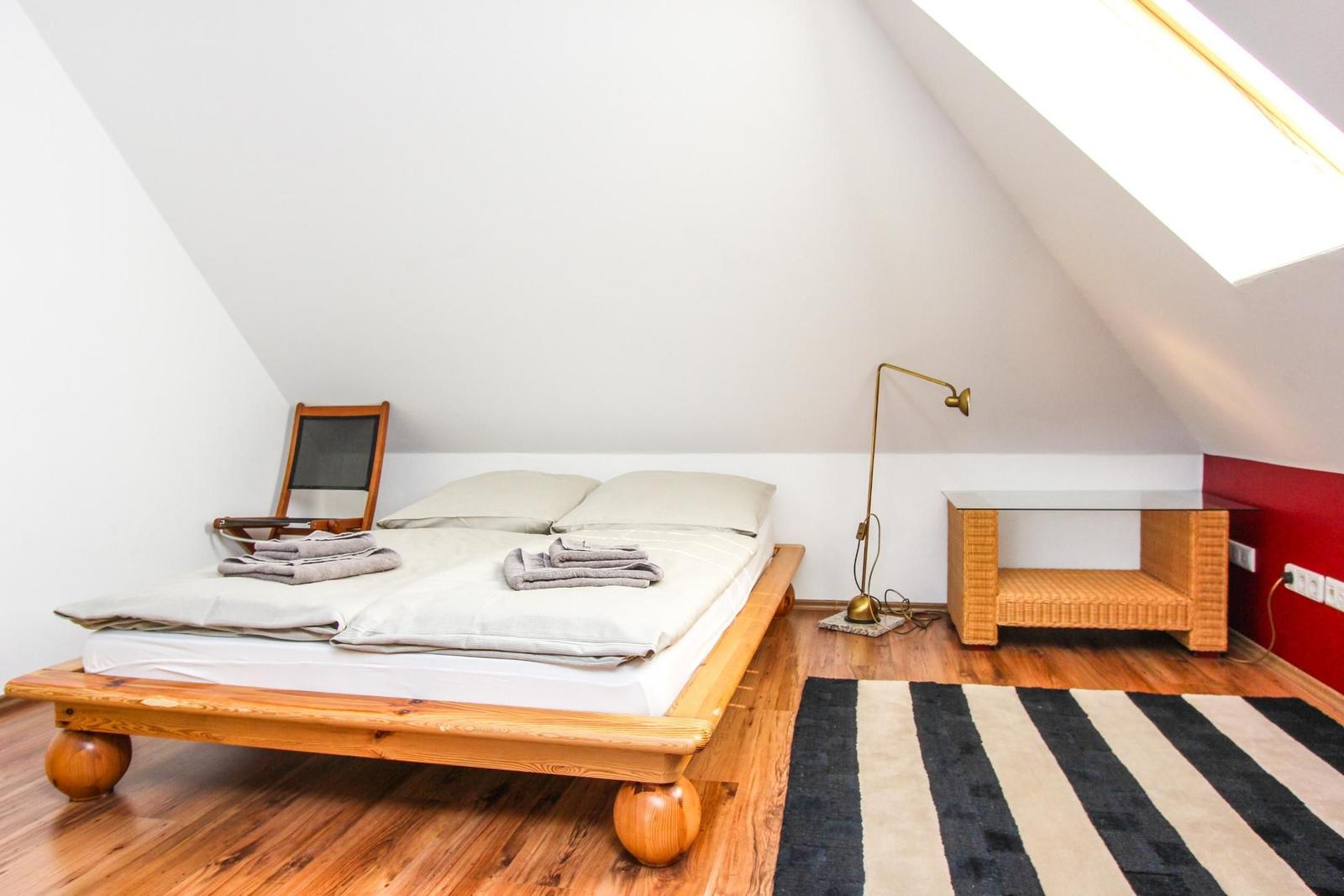 Schlafzimmer mit Holzbett, Schreibtisch und Fenster