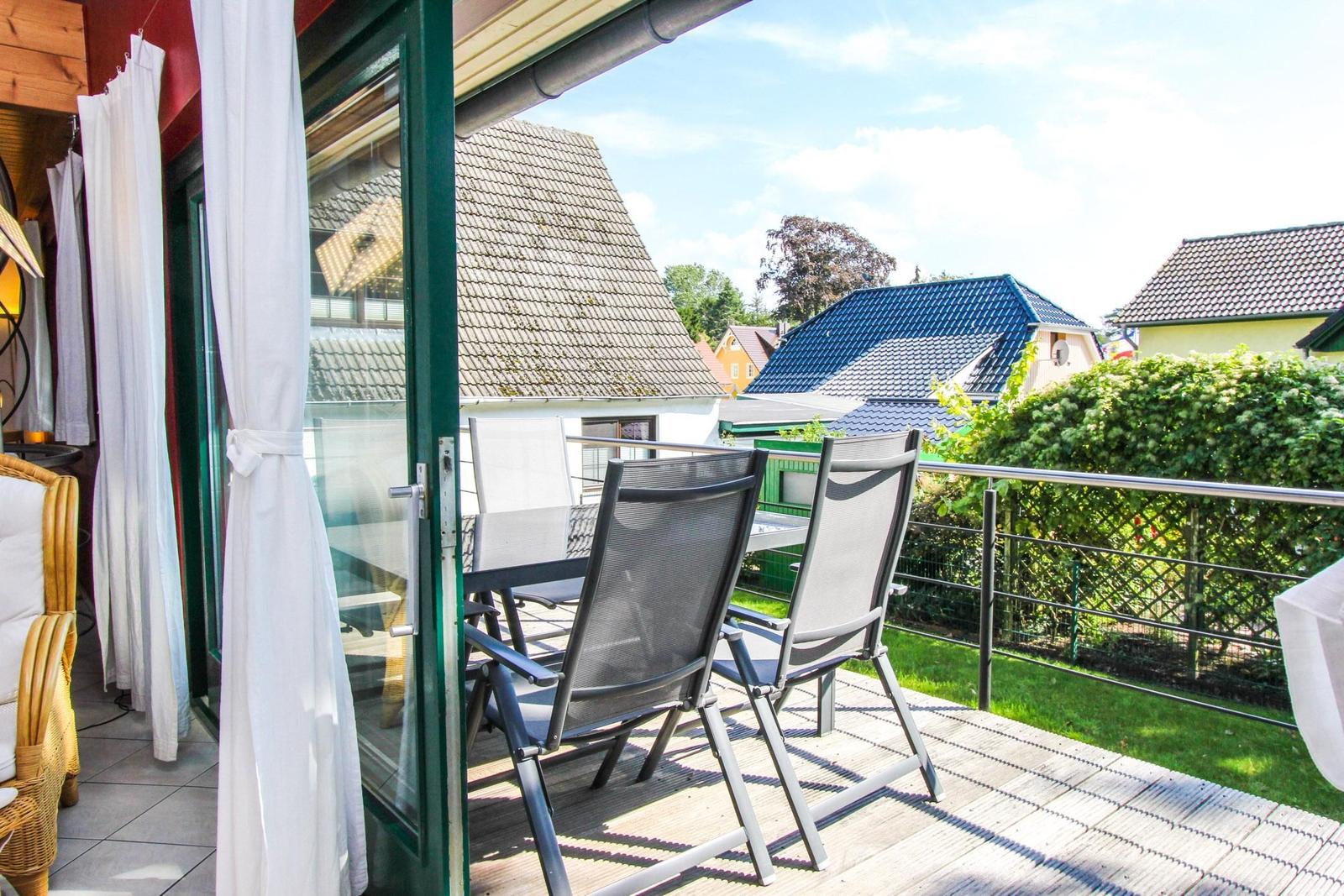 Terrasse mit zwei Stühlen und Tisch. Blick auf Häuser und Grünflächen.