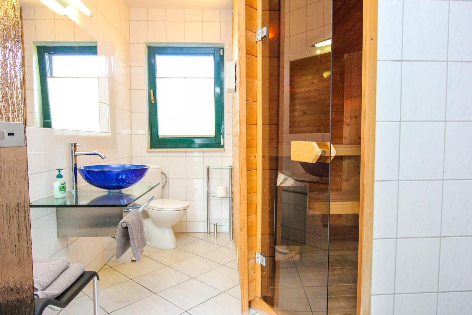 Badezimmer mit Sauna, blauem Waschbecken und Toilette