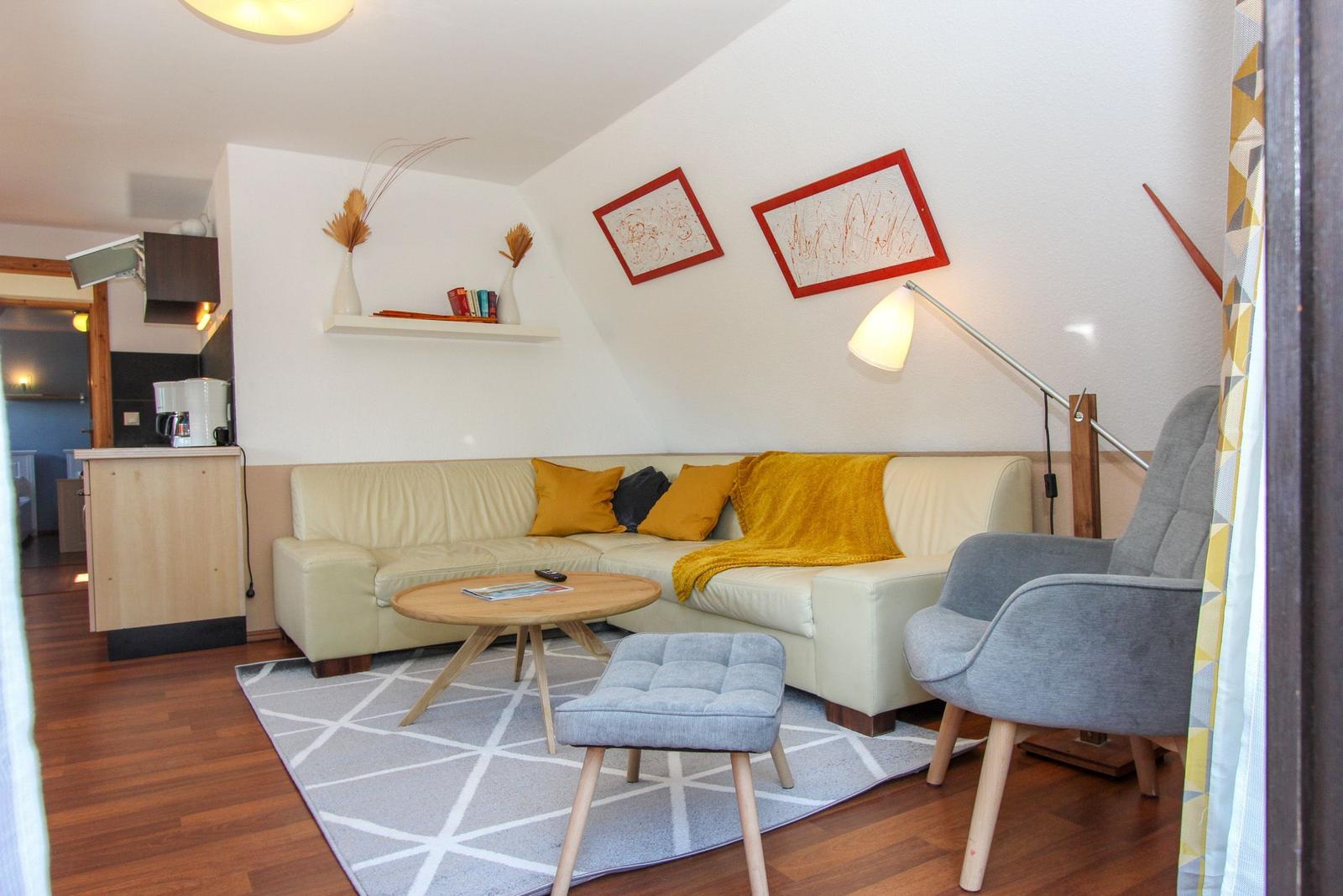 Wohnzimmer mit Sofa, Stuhl und Tisch. Wand mit Bildern und Regal.