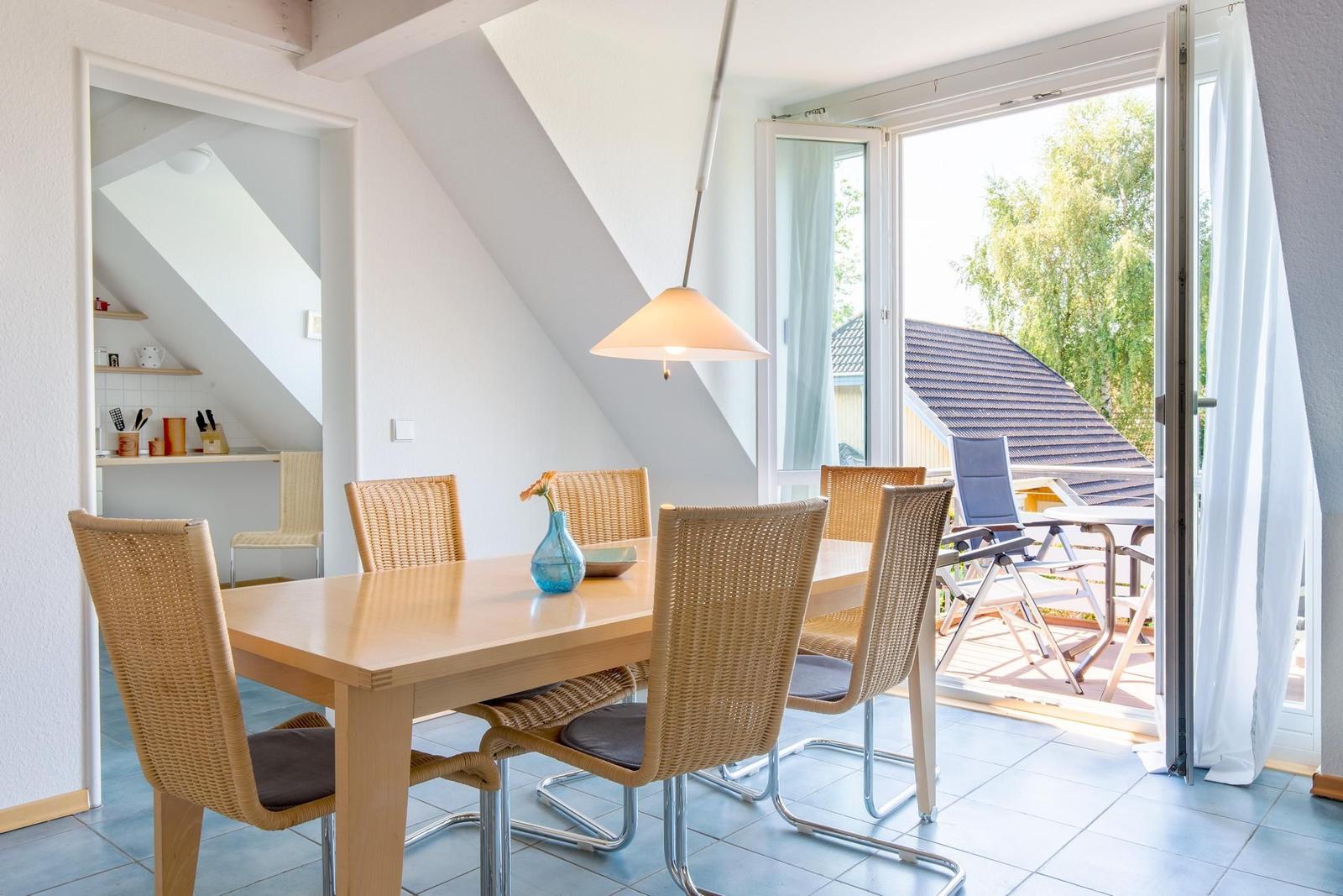 Esszimmer mit Tisch und Stühlen, Blick auf Balkon mit Garten.