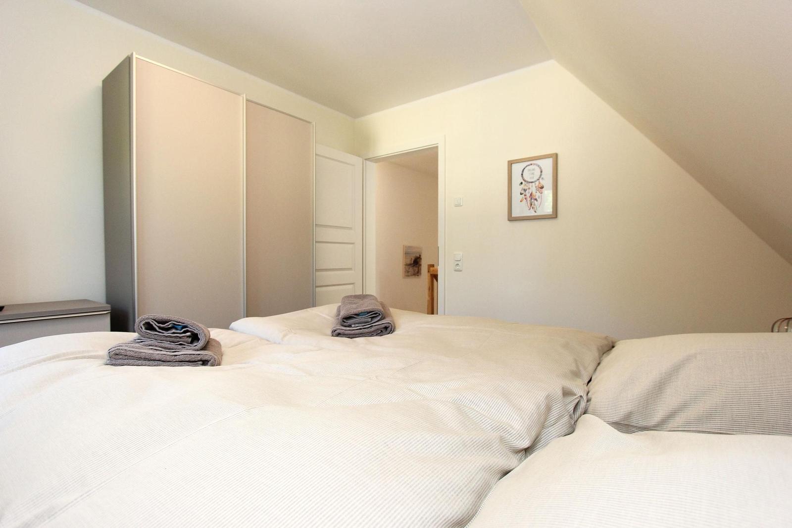 Schlafzimmer mit Doppelbett, KleiderSchrank und Bild an der Wand.