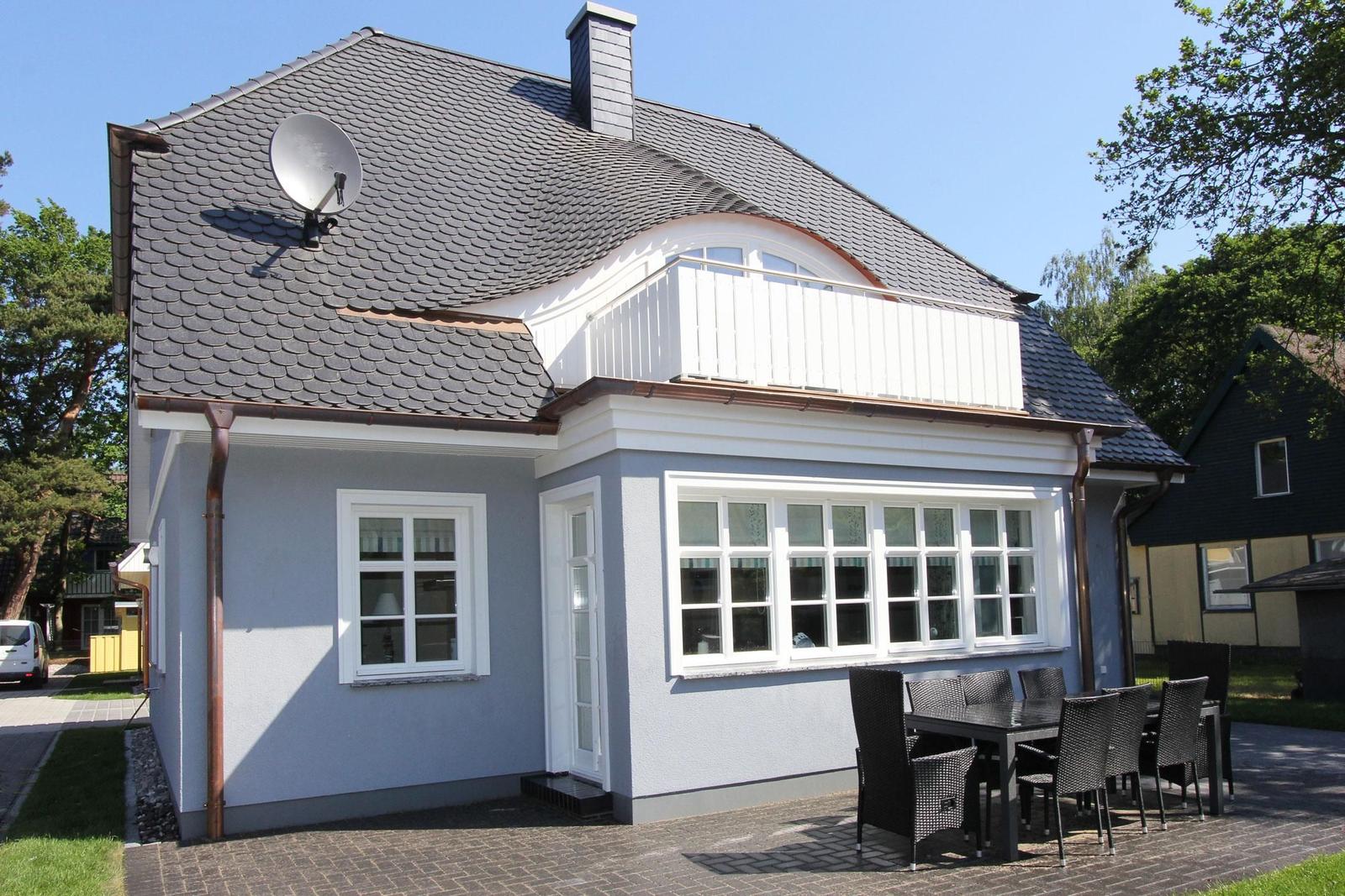 Ein Haus mit Balkon, Satellitenschüssel und Terrasse mit Tisch und Stühlen.