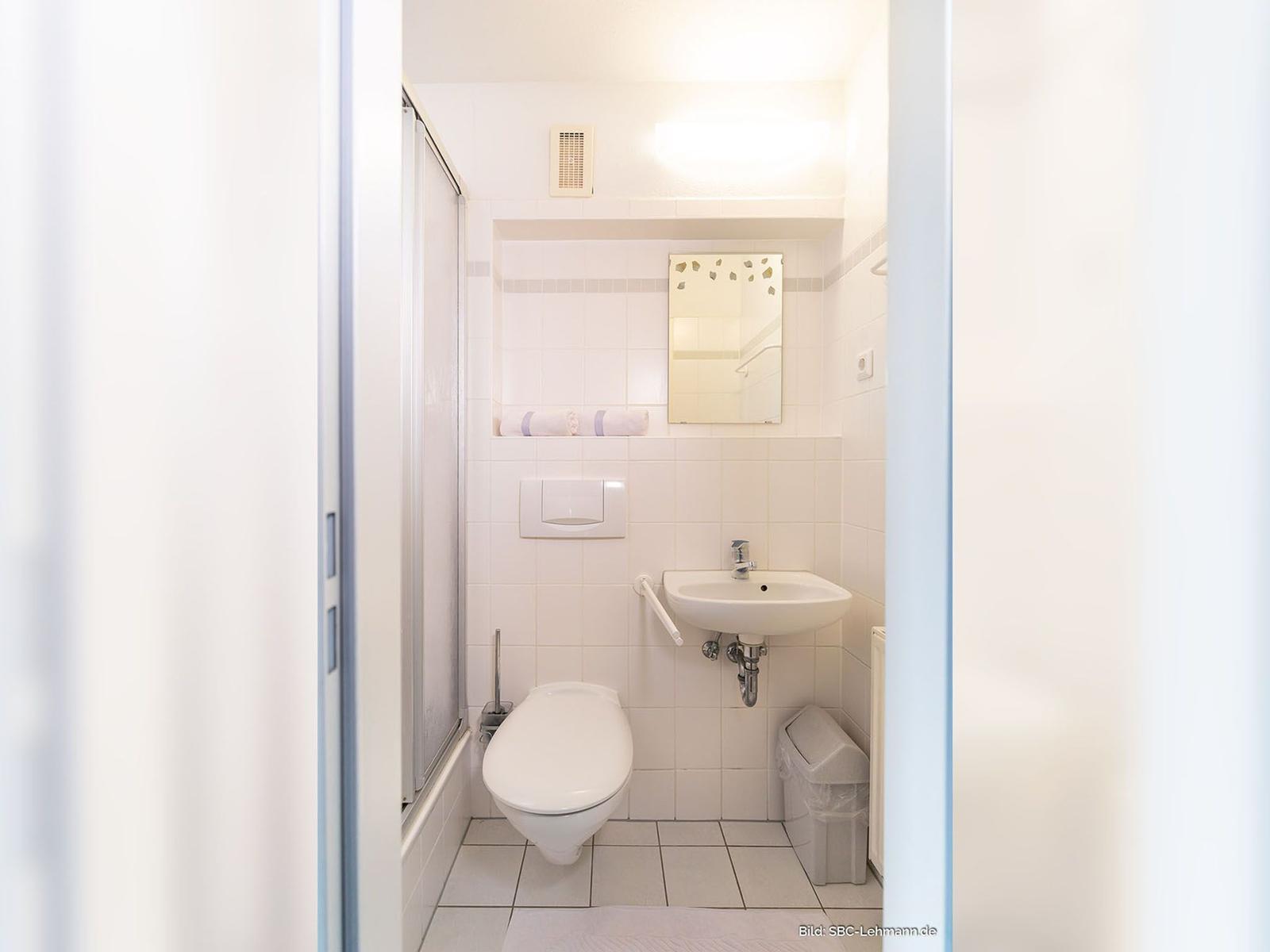 Badezimmer mit Dusche, Toilette und Waschbecken.