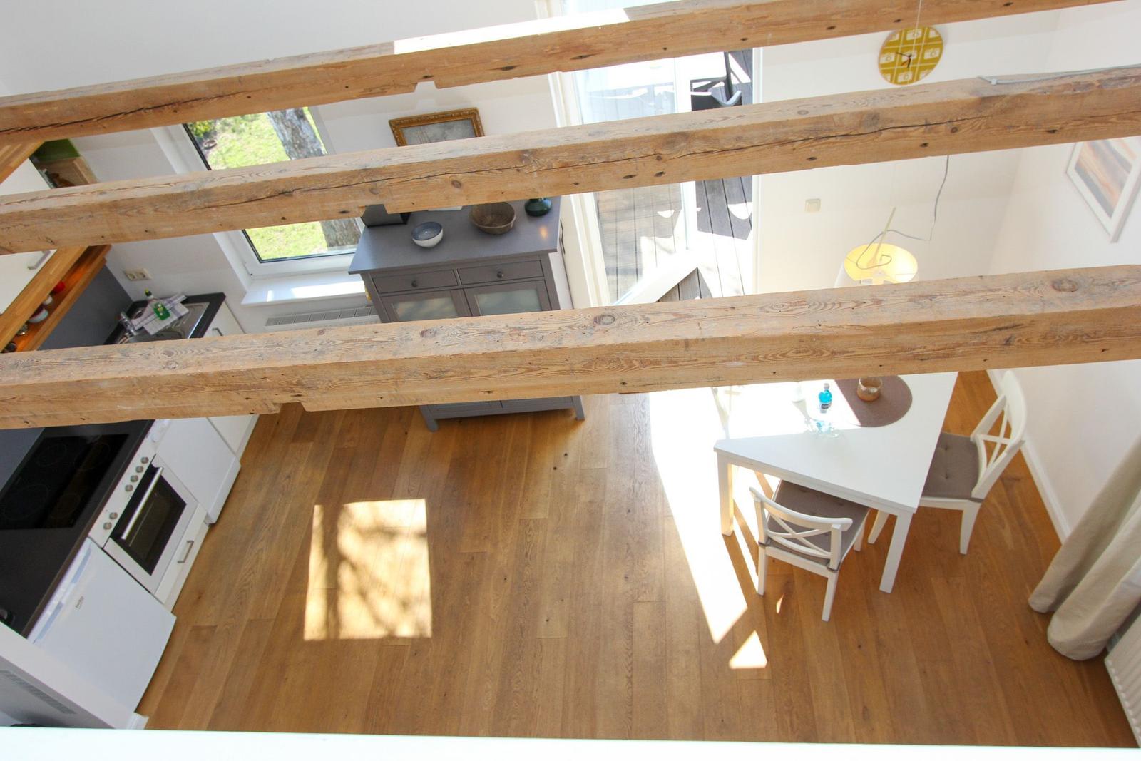 Haus mit Holzbalken, Küchenbereich und Essbereich mit Tisch und Stühlen.