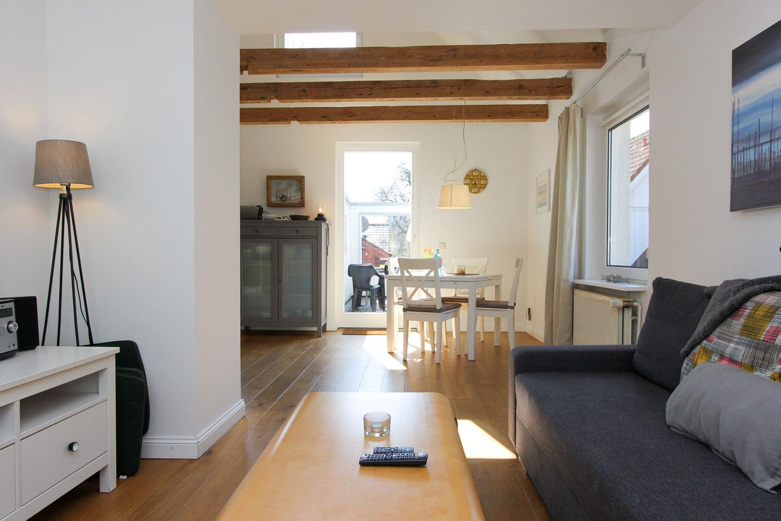Wohnzimmer mit Sofa, Couchtisch und Blick in Essbereich mit Tisch und Stühlen.