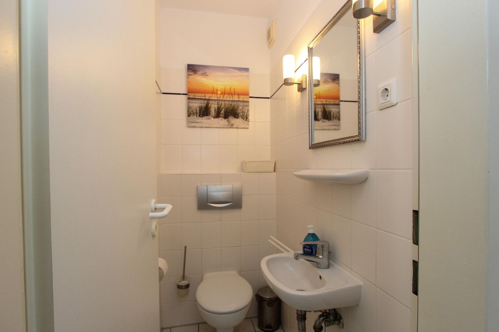Badezimmer mit Toilette, Waschbecken und Spiegel an der Wand.