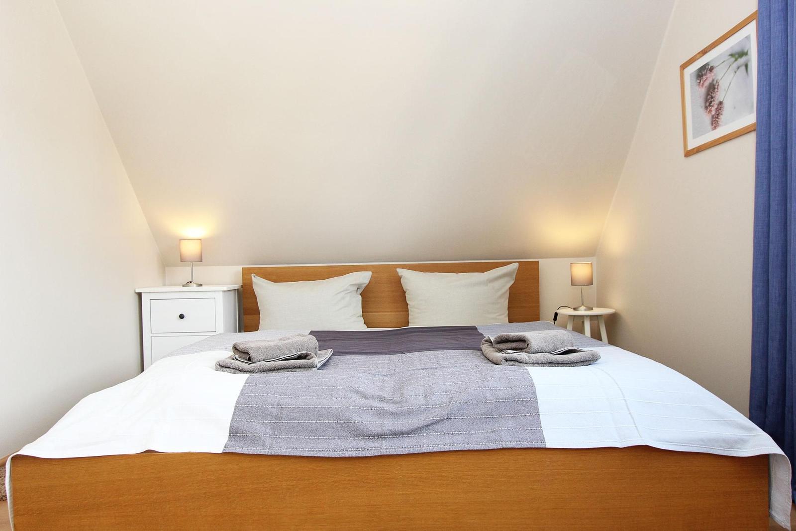 Schlafzimmer mit Doppelbett, zwei Nachttischen und Stehlampe.