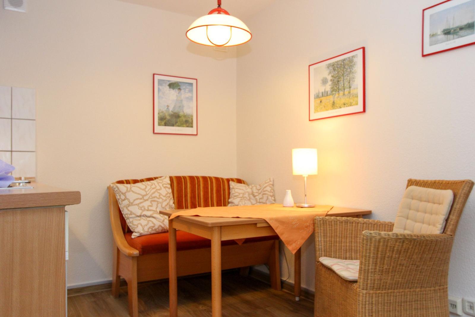 Ein Essbereich mit Tisch, Stuhl und Sofa. An den Wänden hängen Bilder.