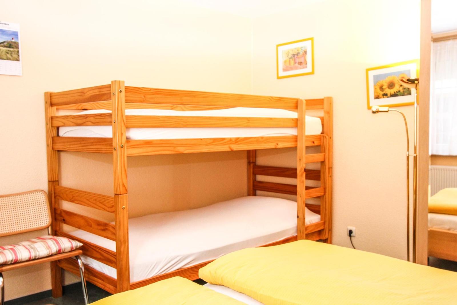 Ein Raum mit einem Holz-Kinderbett und einem Bett mit gelbem Bettzeug.