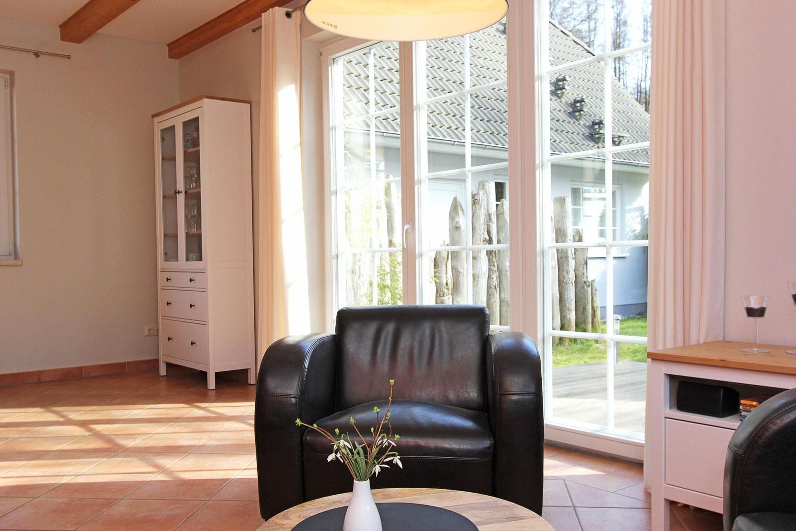 Ein Raum mit braunem Ledersofa, weißem Schrank und großen Fenstern zum Garten.