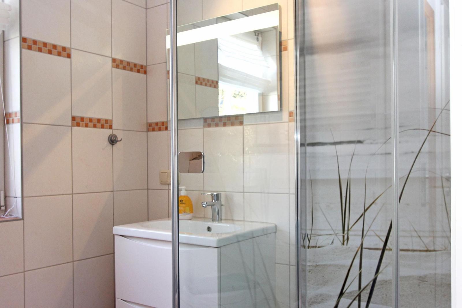 Badezimmer mit Dusche, Waschbecken und Spiegel