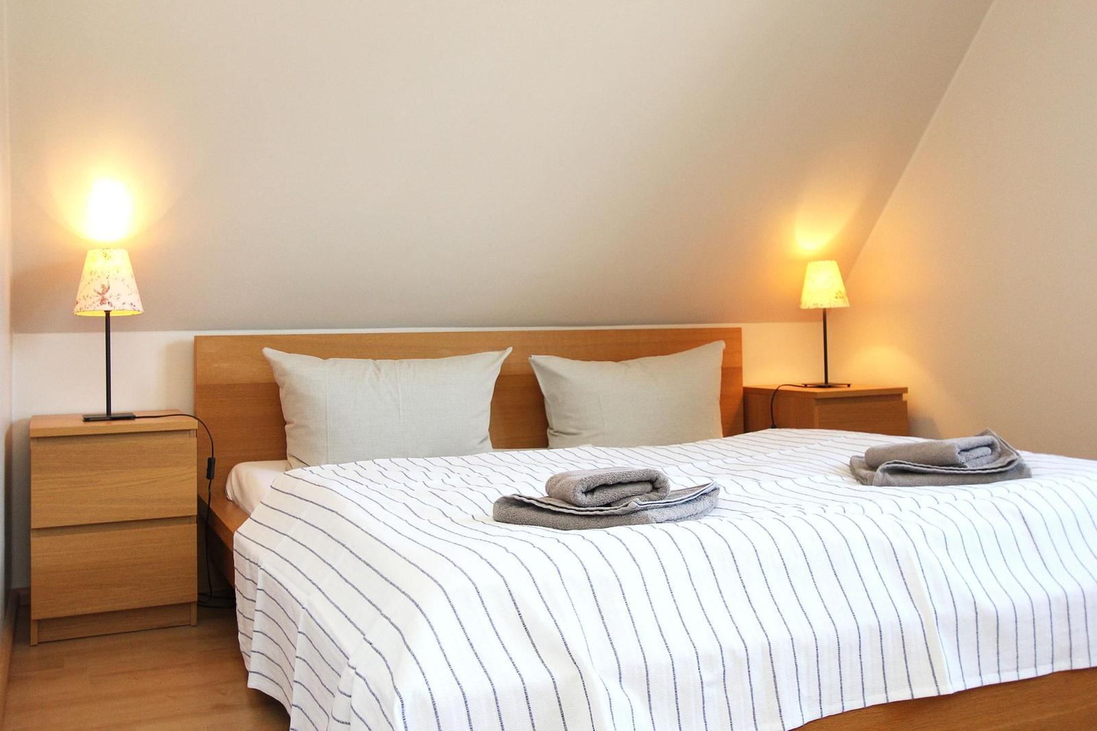 Schlafzimmer mit Doppelbett, zwei Nachttischen und Beleuchtung.