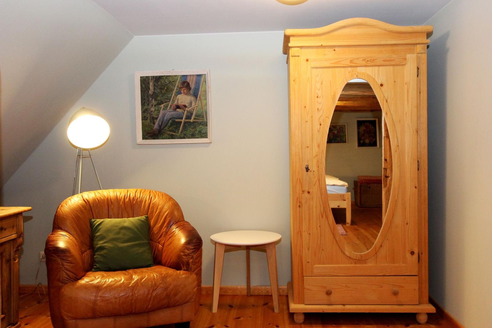 Ein Raum mit einem braunen Ledersessel, einem Holzschrank und einer Stehlampe.