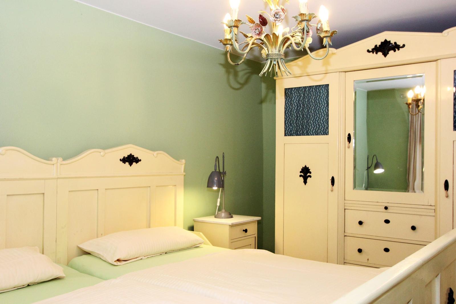 Schlafzimmer mit Bett, Kleiderschrank und Kronleuchter an der Decke.