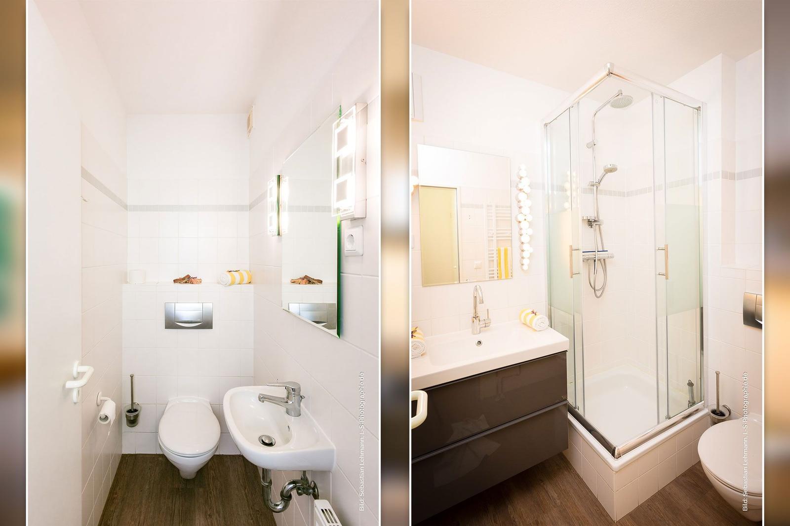 Badezimmer mit Dusche, Waschbecken und Toilette. Weiße Fliesen und Holzboden.