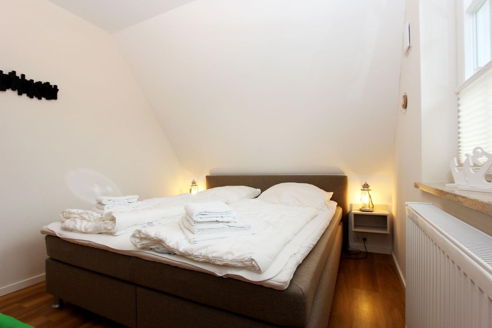 Schlafzimmer mit Bett, Nachttisch und Fenster