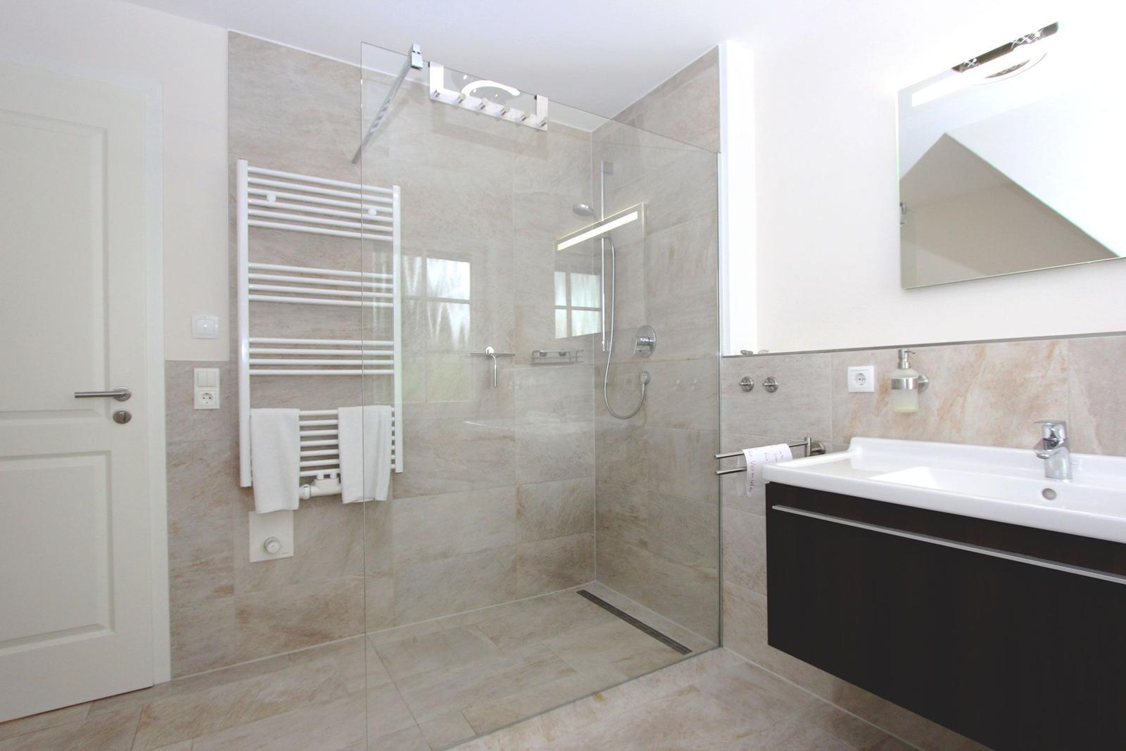 Badezimmer mit Dusche, Handtuchhalter und Waschbecken.