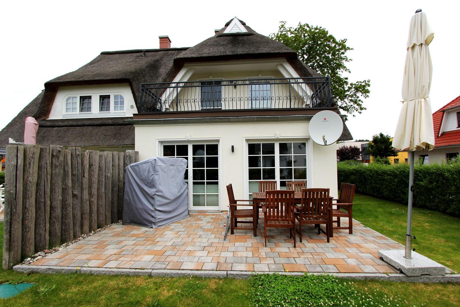 Haus mit Dachterrasse, Terrasse mit Tisch und Stühlen, Satellitenschüssel und Garten.