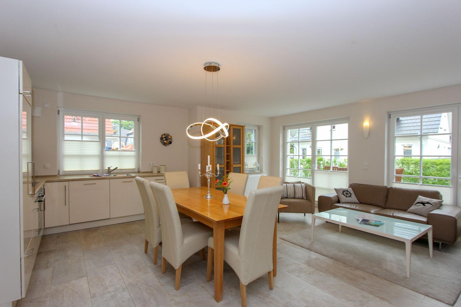 Ein Essbereich mit Tisch und Stühlen neben einem Wohnzimmer mit Sofa und Couchtisch.