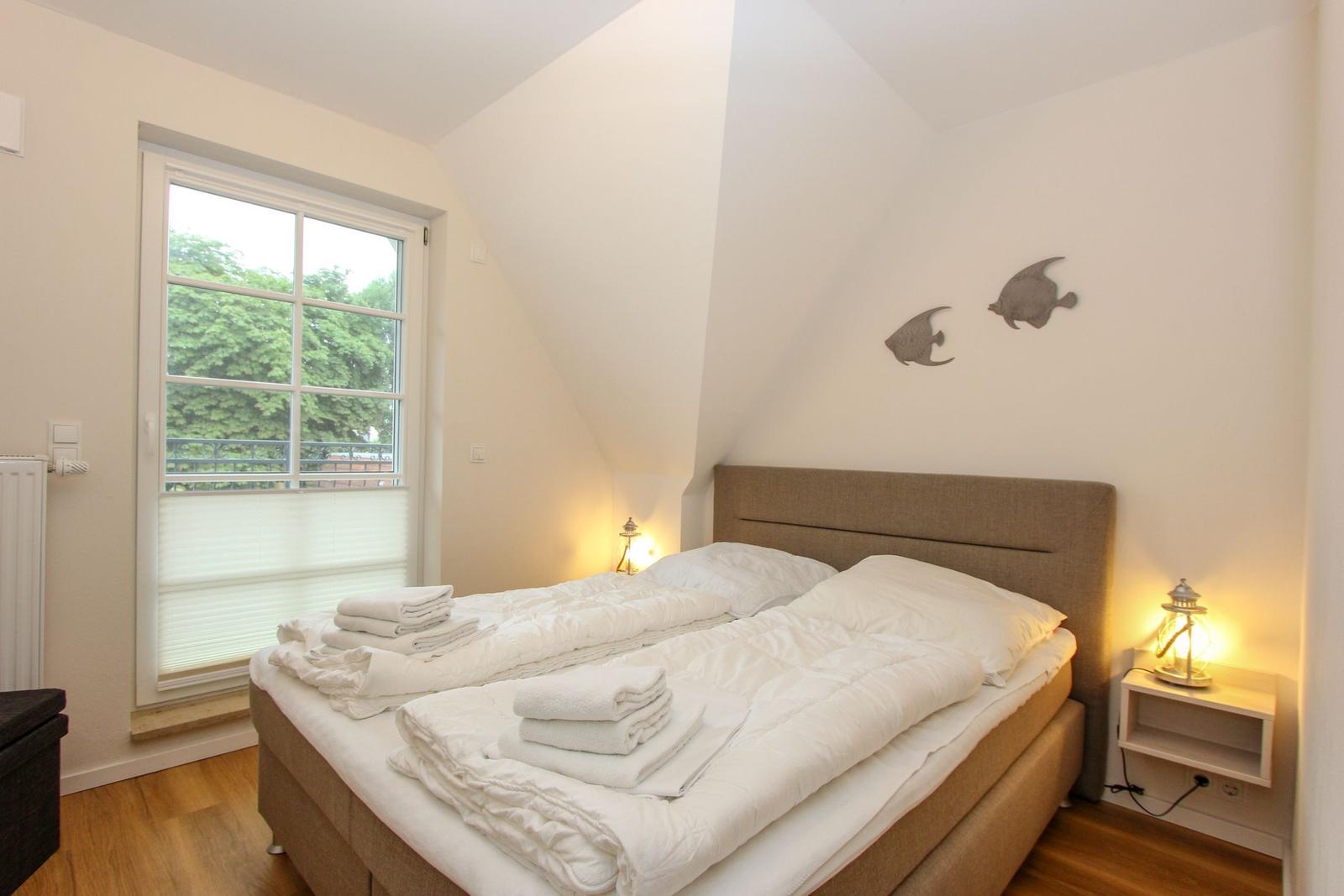 Schlafzimmer mit Doppelbett, Fenster und Wanddekoration.